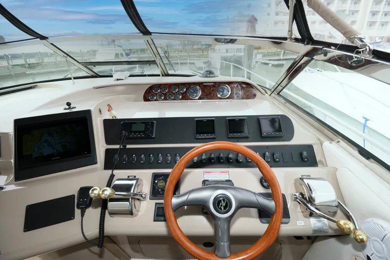 Slide: The Image of 1998 Sea Ray 450 Sundancer helm with wood steering wheel and modern navigation controls. - 6
