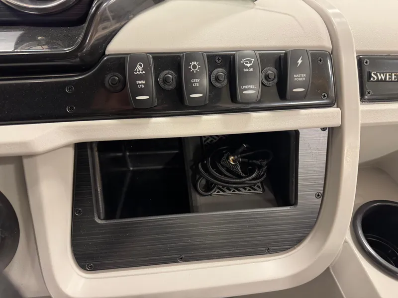 Slide: The Image of Control panel of 2025 Godfrey Sweetwater Entertainment boat with various switches and storage compartment. - 18