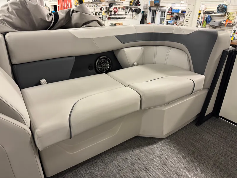 Slide: The Image of 2025 Godfrey Sweetwater Entertainment boat seating in showroom, featuring gray upholstery and integrated speaker. - 25