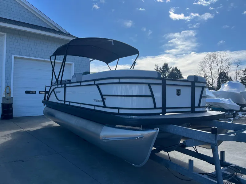 Slide: The Image of 2025 Godfrey Sweetwater Entertainment pontoon boat on trailer, parked outdoors. - 4
