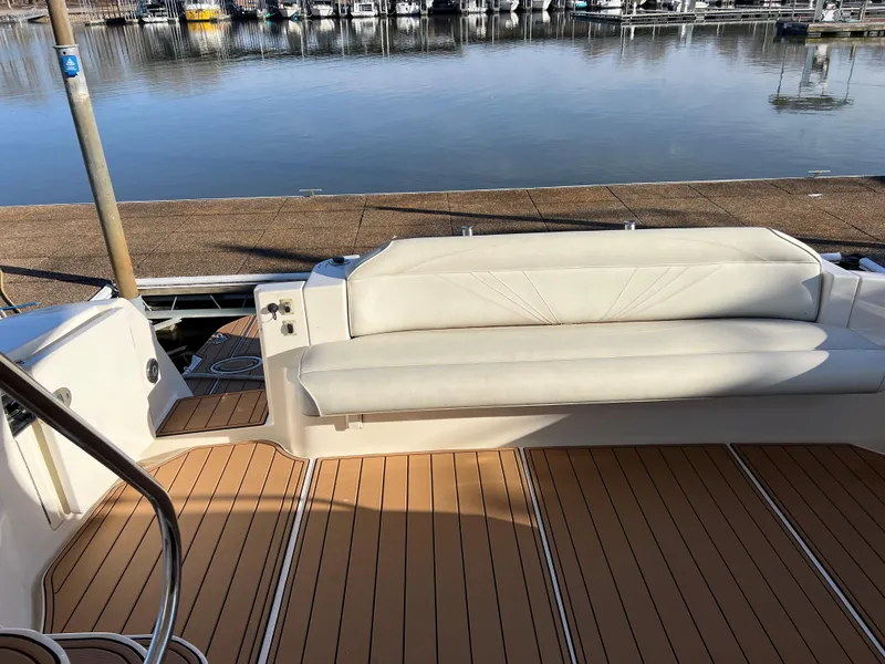 Slide: The Image of 2008 Ovation 52 yacht with white seating and wooden deck by the water. - 9