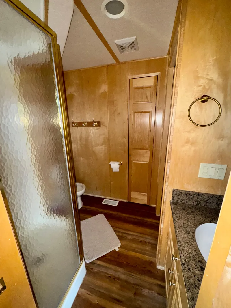 Slide: The Image of Wood-paneled bathroom with shower, granite countertop, and wooden flooring in a 2000 Fantasy Escape From LA model. - 10