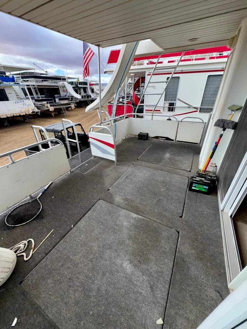 Slide: The Image of Houseboat deck with cleaning tools, docked alongside other boats, featuring an American flag. - 19