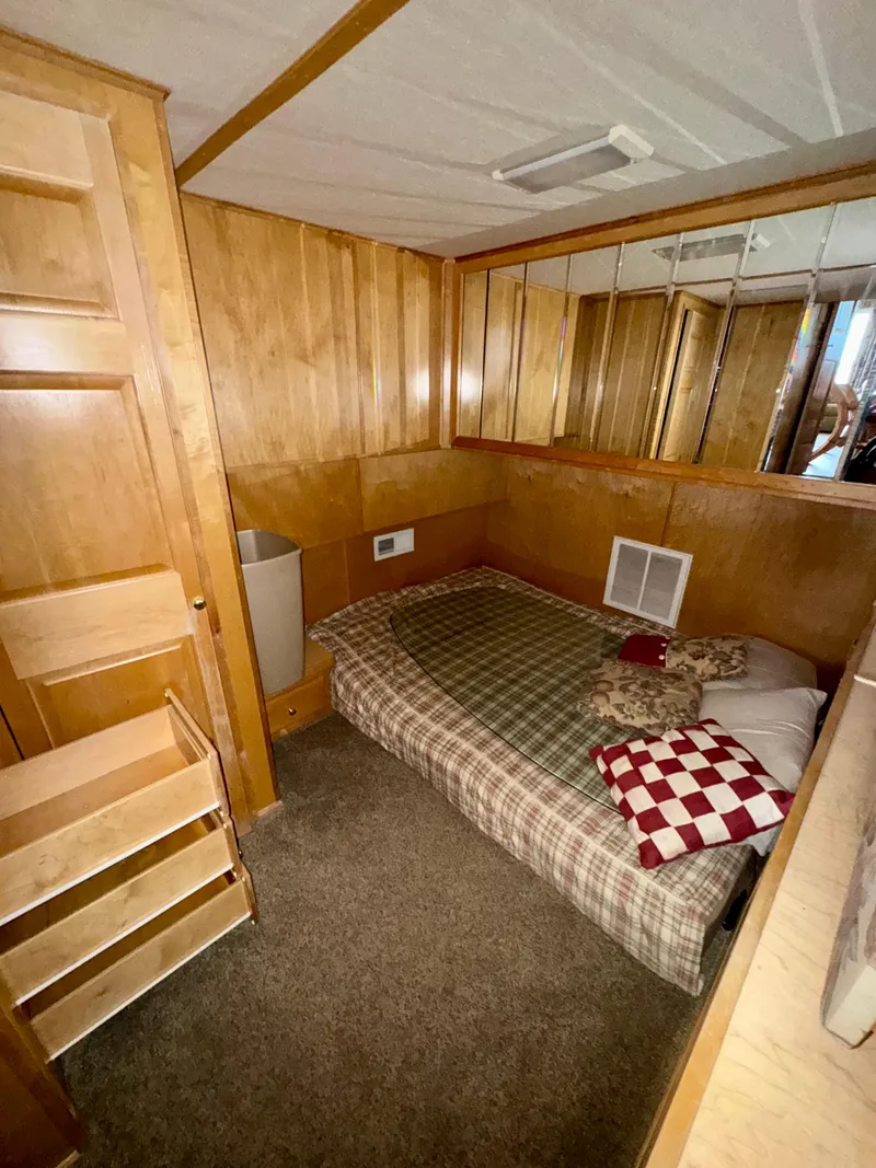 Slide: The Image of Cozy wooden interior with a bed, checkered pillows, and mirrored wall in a compact room. - 7