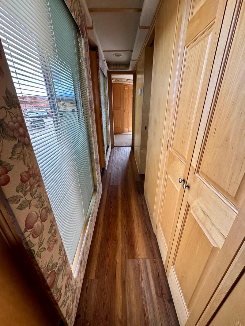 Slide: The Image of Narrow hallway in a 2000 Fantasy Escape From LA RV with wood paneling and floral curtains. - 9