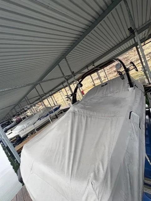 Slide: The Image of 2005 Malibu Sunsetter 23 XTi boat covered and docked under a metal roof. - 1