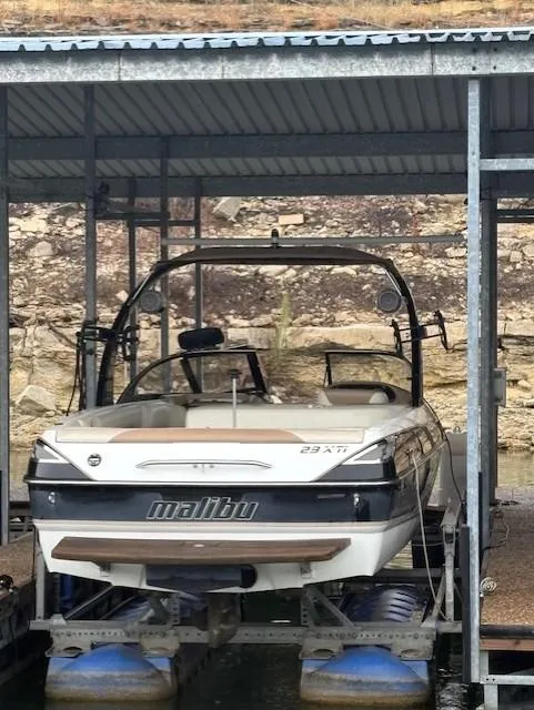 Slide: The Image of 2005 Malibu Sunsetter 23 XTi boat docked under a metal canopy. - 2
