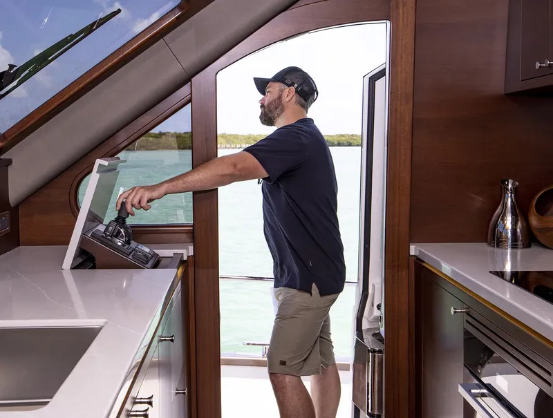 Slide: The Image of Man operating the helm of a 2026 Grand Banks GB 85 yacht interior. - 19