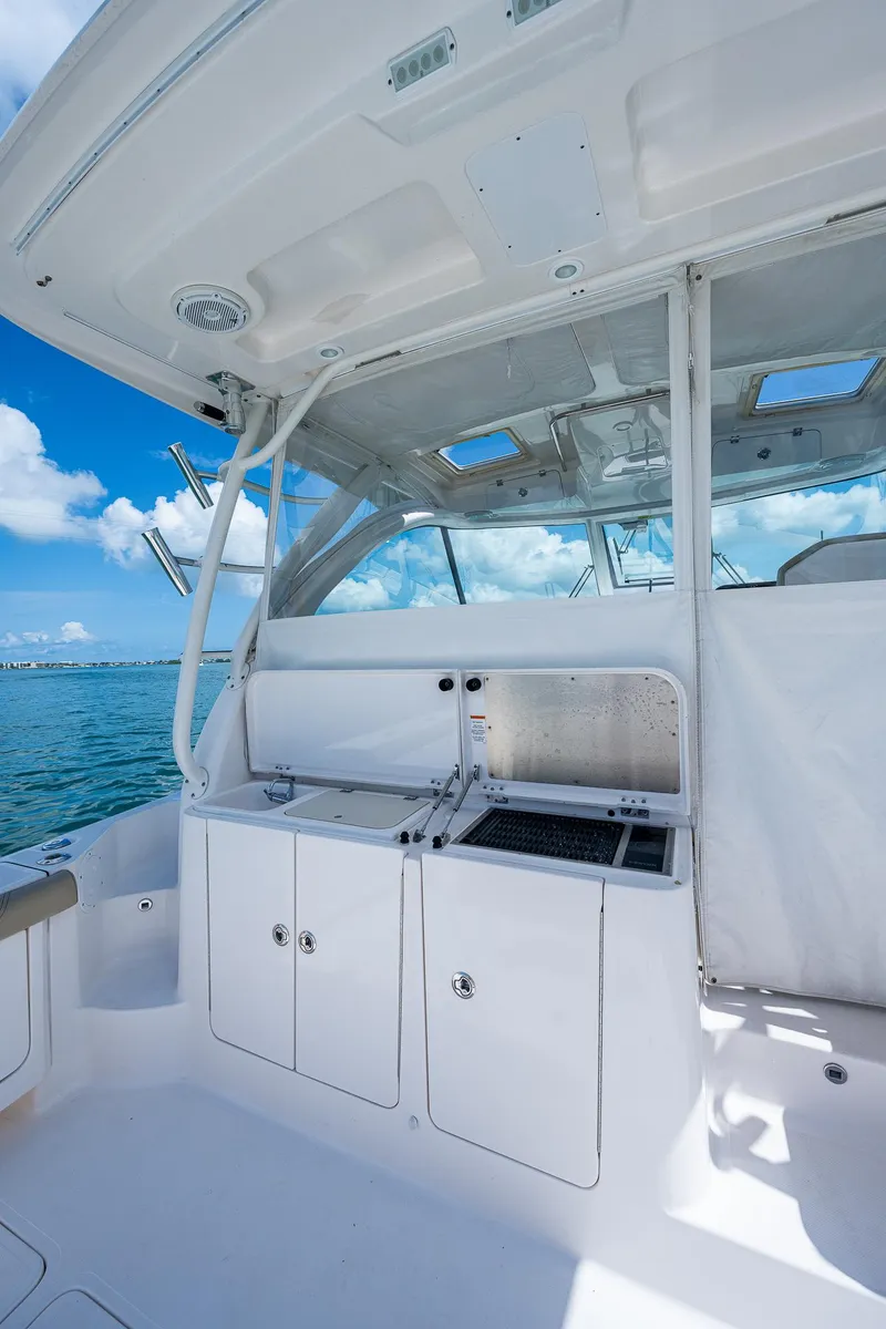 Slide: The Image of 2018 Pursuit OS 385 Offshore boat interior with ocean view, featuring sleek white cabinetry. - 14