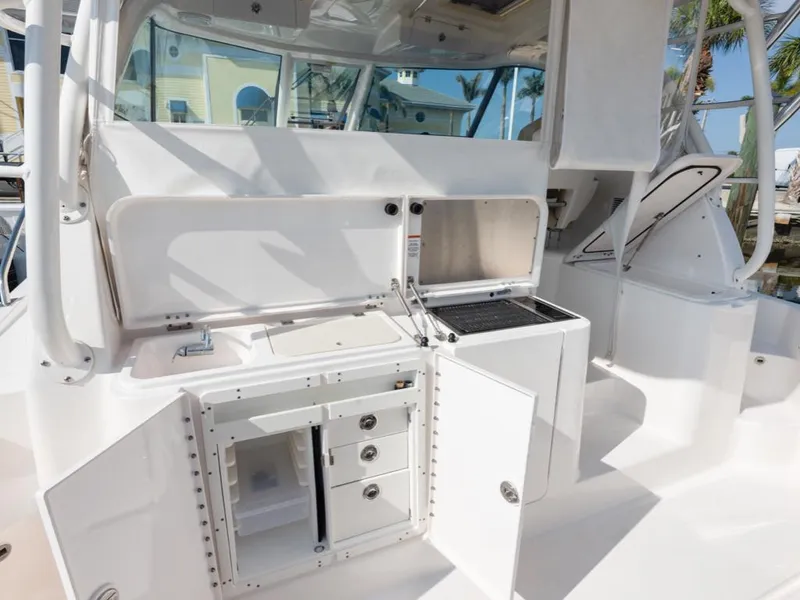 Slide: The Image of 2018 Pursuit OS 385 Offshore boat interior with open storage compartments and grill. - 16