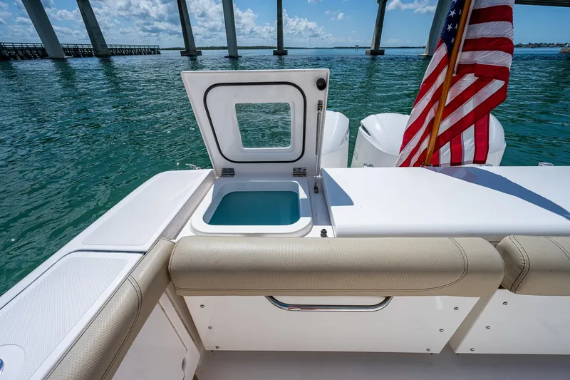 Slide: The Image of 2018 Pursuit OS 385 Offshore boat with open storage compartment, American flag, and ocean view. - 18