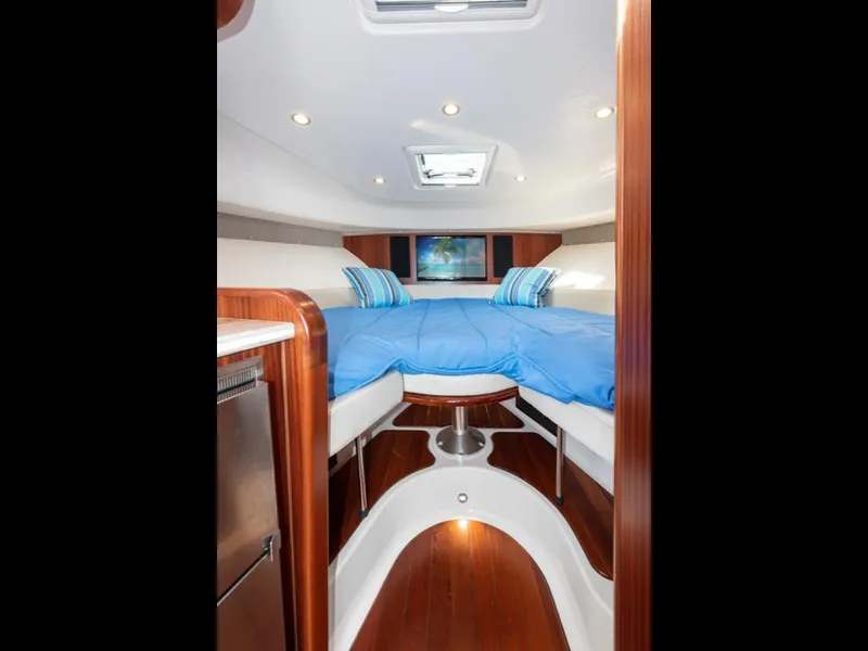 Slide: The Image of 2018 Pursuit OS 385 Offshore cabin interior with blue bedding and wood accents. - 37