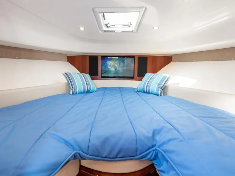 Slide: The Image of Interior of 2018 Pursuit OS 385 Offshore boat with blue bedding and TV. - 38