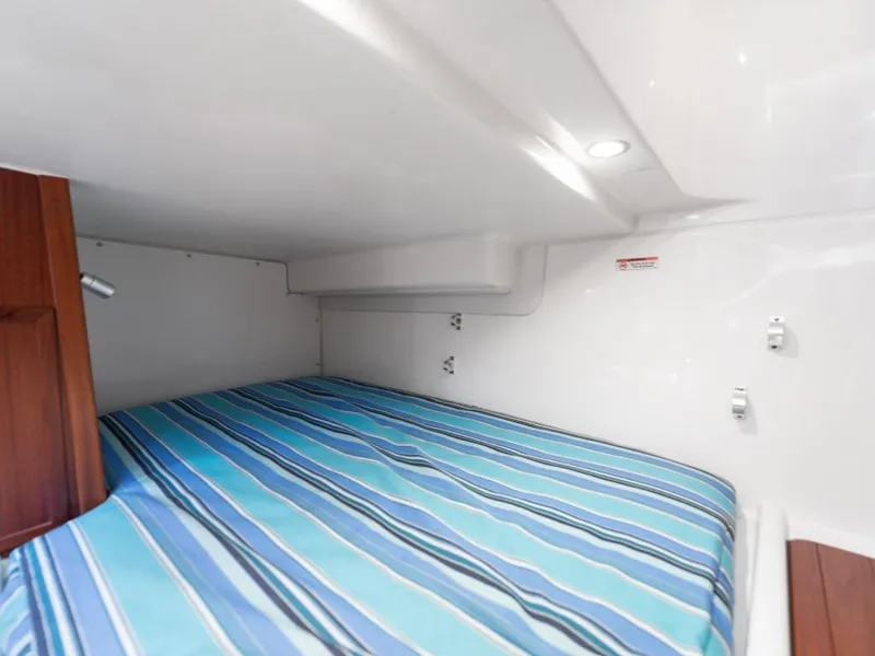 Slide: The Image of 2018 Pursuit OS 385 Offshore cabin with striped bedding, white walls, and wooden accents. - 41