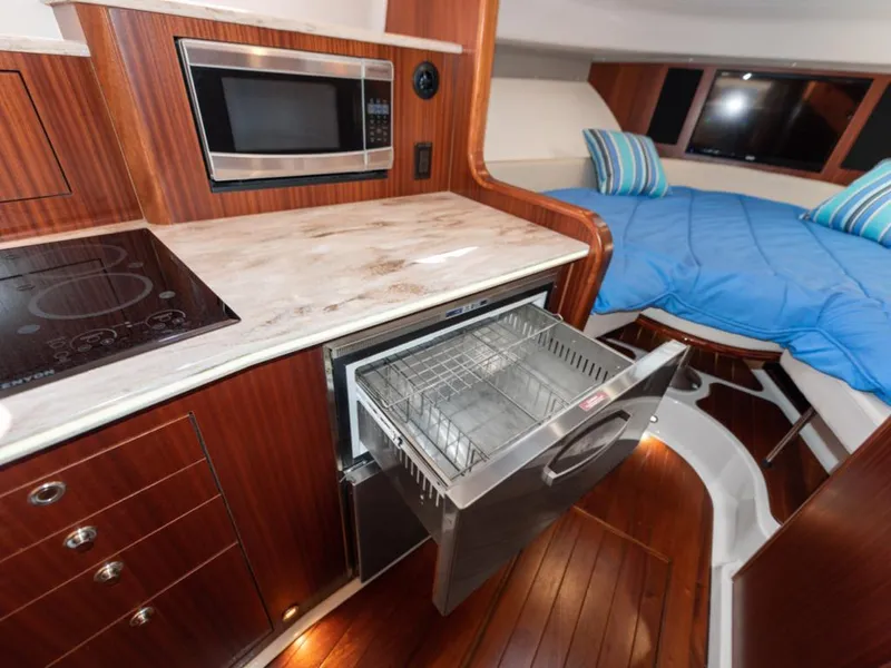 Slide: The Image of 2018 Pursuit OS 385 Offshore interior with kitchen and sleeping area, featuring modern appliances. - 45