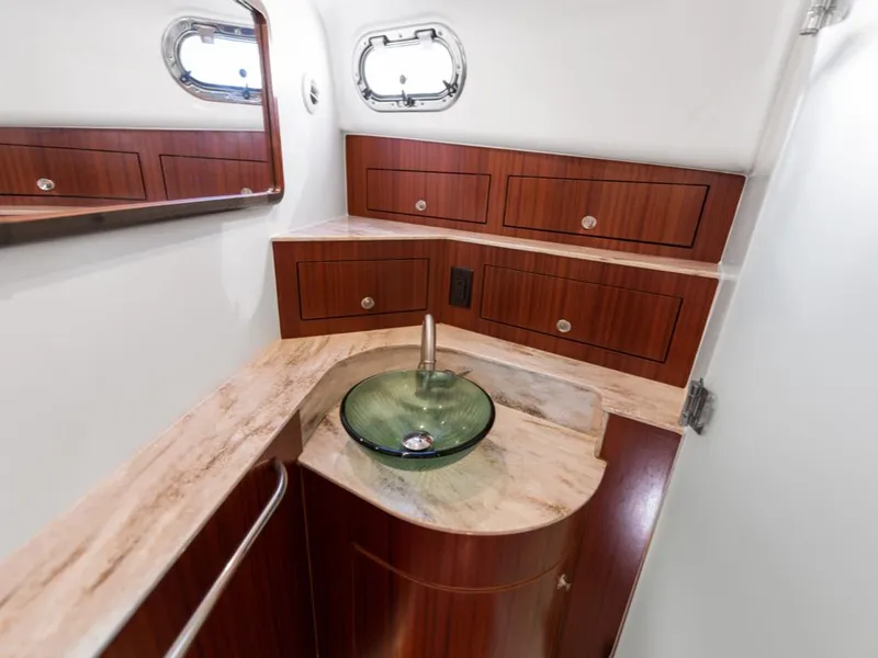 Slide: The Image of 2018 Pursuit OS 385 Offshore bathroom with wood cabinetry and modern glass sink. - 47