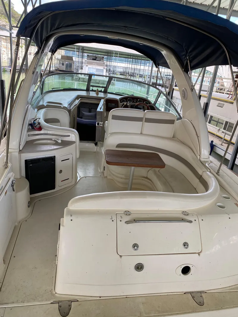Slide: The Image of 2003 Sea Ray 320 Sundancer interior with seating and helm under a blue canopy. - 10