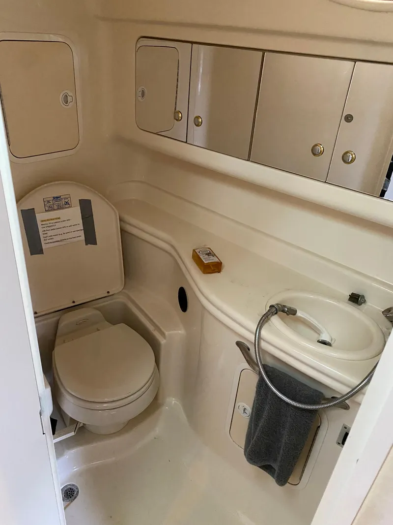 Slide: The Image of 2003 Sea Ray 320 Sundancer bathroom with toilet, sink, and storage cabinets. - 13