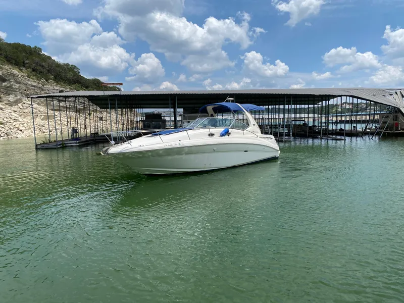 Slide: The Image of 2003 Sea Ray 320 Sundancer boat docked on a serene lake under a partly cloudy sky. - 3