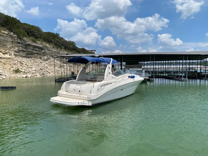 Slide: The Image of 2003 Sea Ray 320 Sundancer docked on a serene lake under a blue sky. - 6