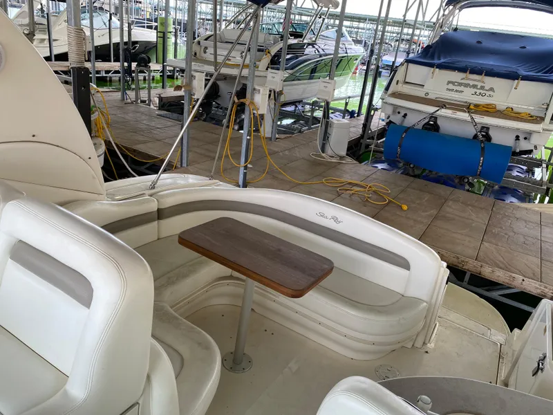 Slide: The Image of 2003 Sea Ray 320 Sundancer interior with seating and table in marina setting. - 7