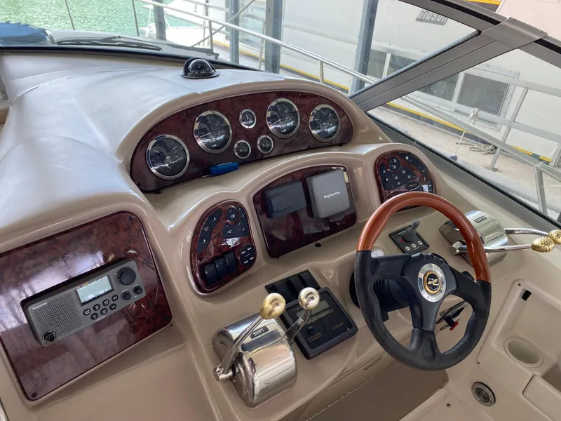 Slide: The Image of 2003 Sea Ray 320 Sundancer helm with gauges, controls, and wood-accented steering wheel. - 9