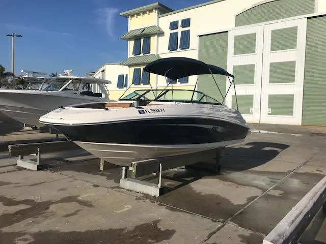 Slide: The Image of 2015 Sea Ray 220 Sundeck Outboard boat on display at a marina. - 0