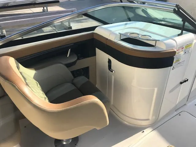Slide: The Image of 2015 Sea Ray 220 Sundeck Outboard interior with beige seating and sleek dashboard design. - 18