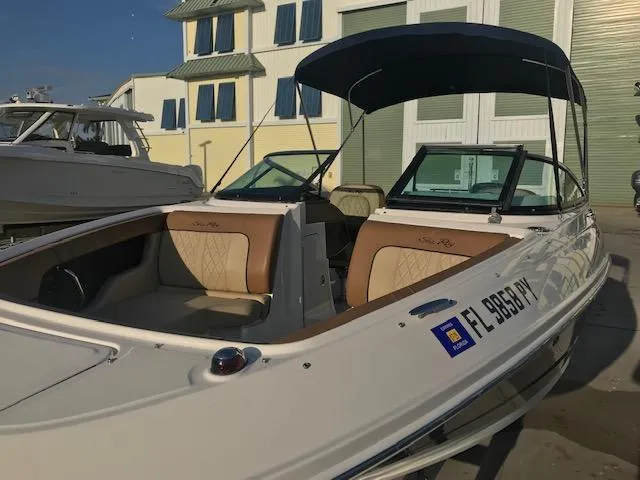 Slide: The Image of 2015 Sea Ray 220 Sundeck Outboard boat with canopy, docked near a building. - 19
