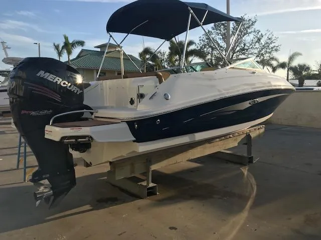 Slide: The Image of 2015 Sea Ray 220 Sundeck Outboard boat with Mercury engine, docked under a canopy. - 29