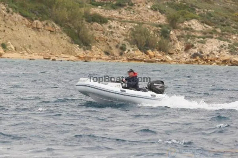 Slide: The Image of 2022 Northstar Axs 3.1 boat cruising on water near rocky shoreline. - 2
