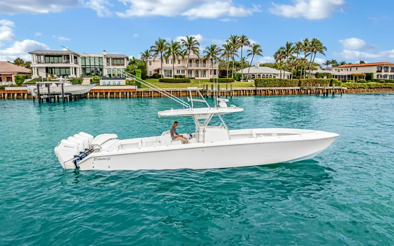Slide: The Image of 2017 Bahama Center Console boat cruising near waterfront homes, clear blue water, and palm trees. - 1