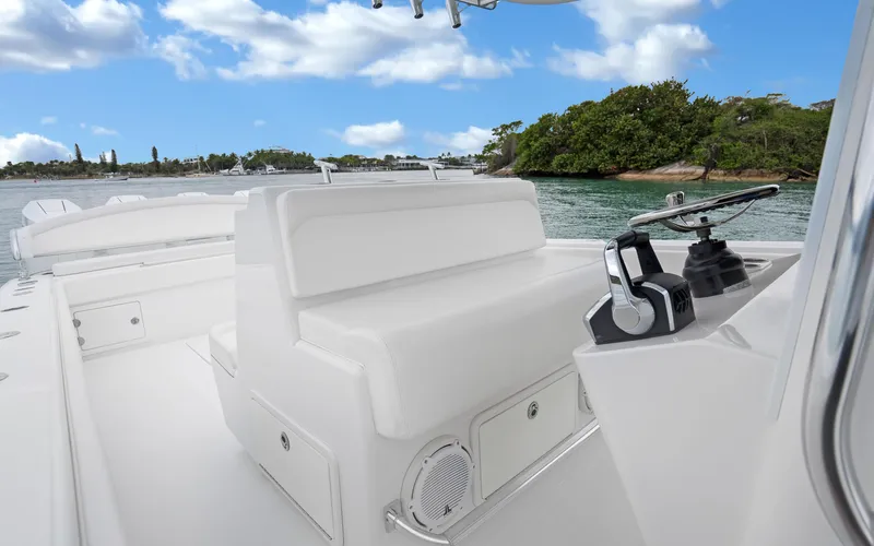 Slide: The Image of 2017 Bahama Center Console boat interior with white seating and control panel, on a scenic waterway. - 14