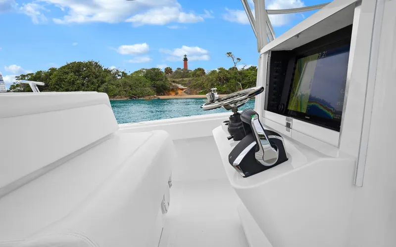 Slide: The Image of 2017 Bahama Center Console boat interior with steering wheel and navigation screen, near scenic shoreline. - 15