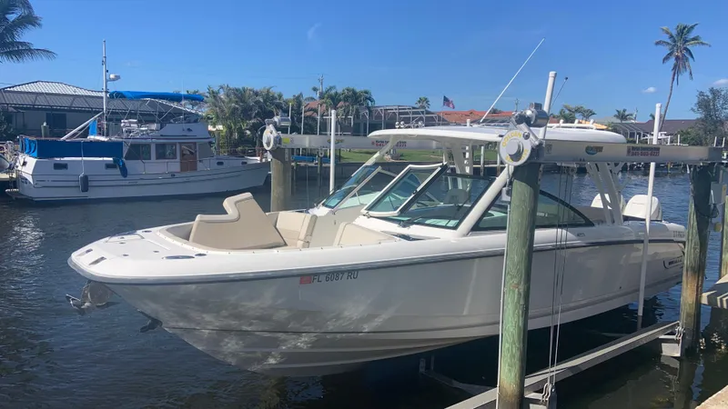 Slide: The Image of 2019 Boston Whaler 320 Vantage boat docked in a sunny marina setting. - 2