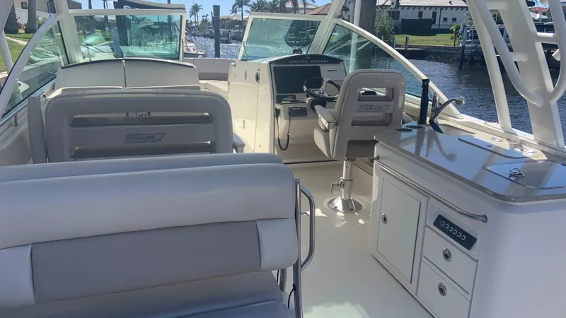 Slide: The Image of 2019 Boston Whaler 320 Vantage interior with seating and helm, docked by the water. - 3