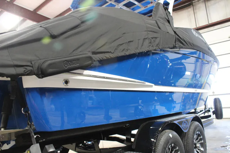 Slide: The Image of 2025 Cobalt R6 boat in blue with a black cover, on a trailer indoors. - 12