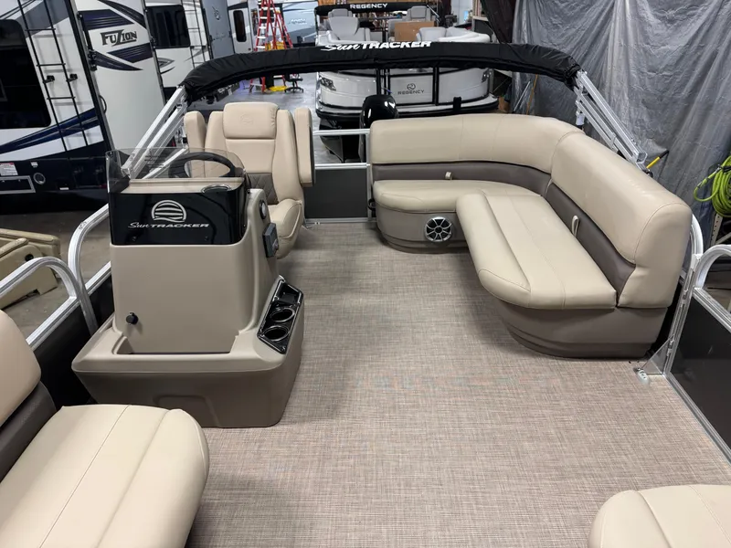 Slide: The Image of 2025 Sun Tracker Party Barge 16 DLX interior with beige seating and steering console. - 12