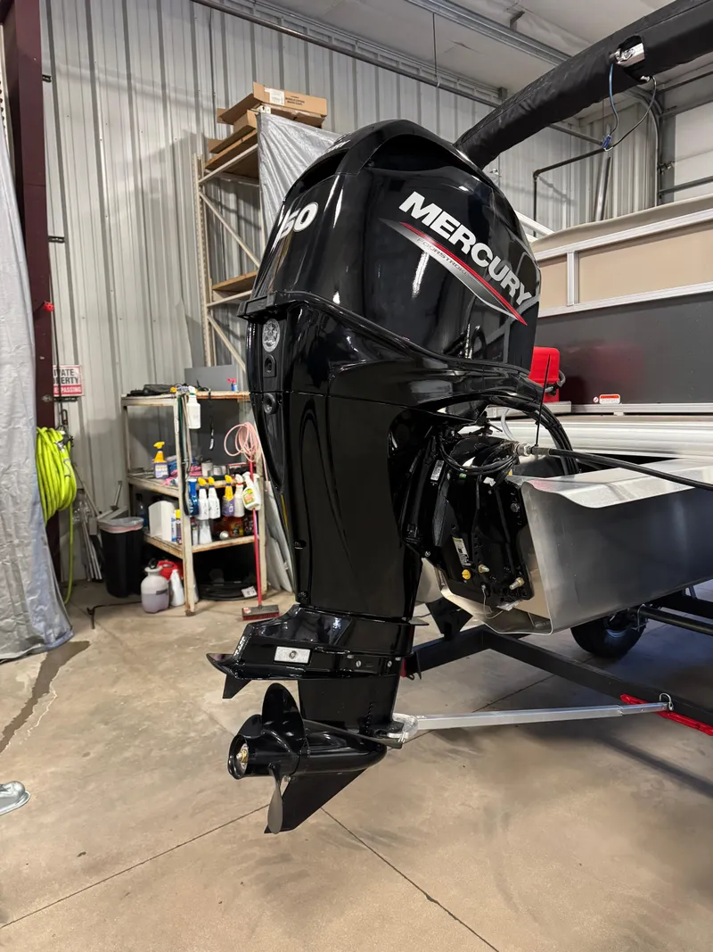 Slide: The Image of 2025 Sun Tracker Party Barge 16 DLX with Mercury outboard motor in a garage. - 4