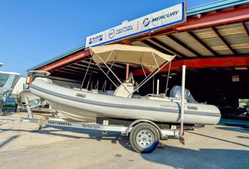 Slide: The Image of 2023 Northstar Axis 4.8 RIB boat on trailer under a canopy at a dealership. - 3
