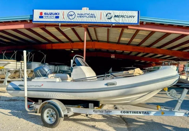 Slide: The Image of 2023 Northstar Axis 4.8 RIB boat on trailer, displayed at dealership with Suzuki and Mercury signage. - 1