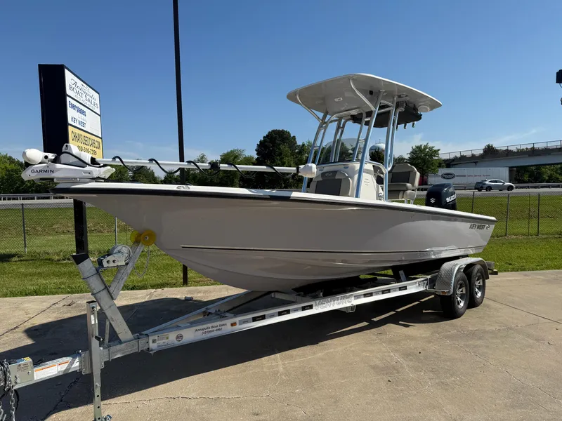Slide: The Image of 2025 Key West 230 Bay Reef boat on trailer, parked outdoors under clear sky. - 2