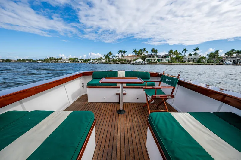 Slide: The Image of Blackfin 28 CC 2010 boat interior with green seating, wooden deck, and scenic waterfront view. - 5
