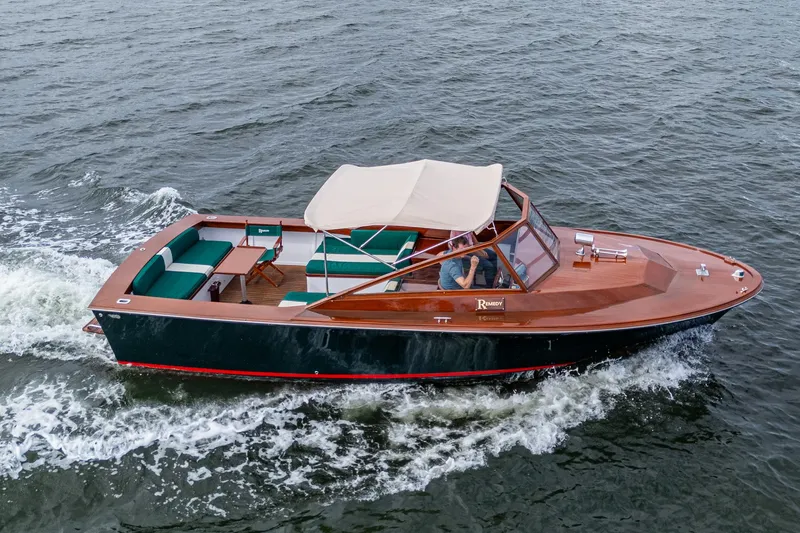 The Image of 2010 Blackfin 28 CC boat cruising on water with a beige canopy and wooden deck. - 1