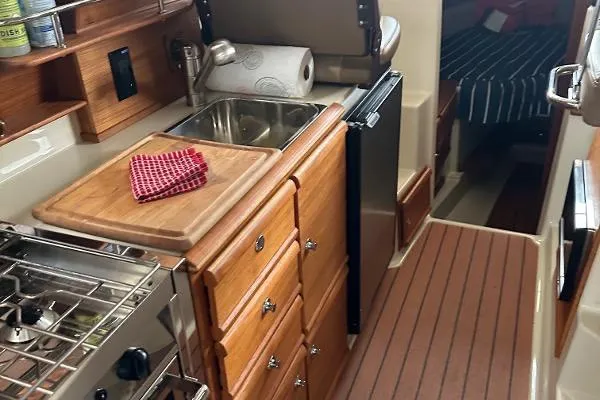 Slide: The Image of 2021 Ranger Tugs R-27 galley with wooden cabinetry, sink, and compact appliances. - 17