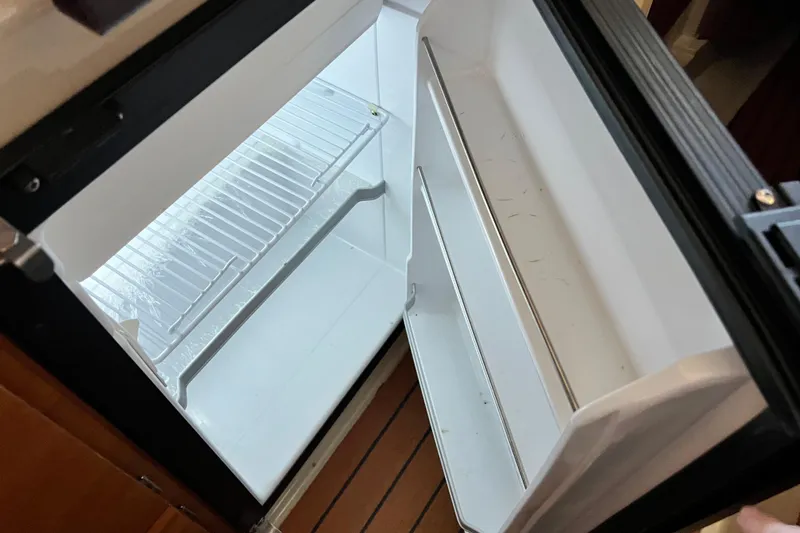 Slide: The Image of Open refrigerator inside a 2020 Ranger Tugs 27 boat, showing empty shelves. - 14