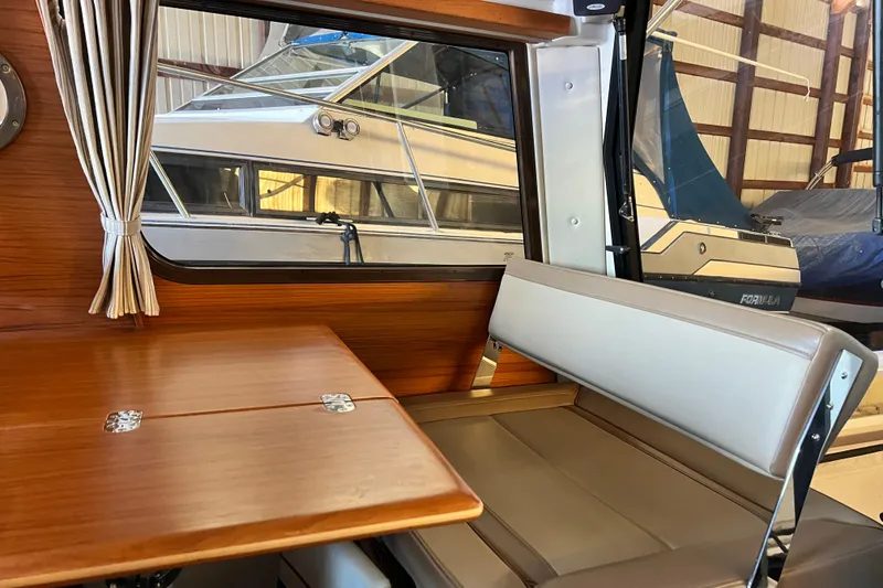 Slide: The Image of Interior of 2020 Ranger Tugs 27, featuring a wooden table and cushioned seating. - 8