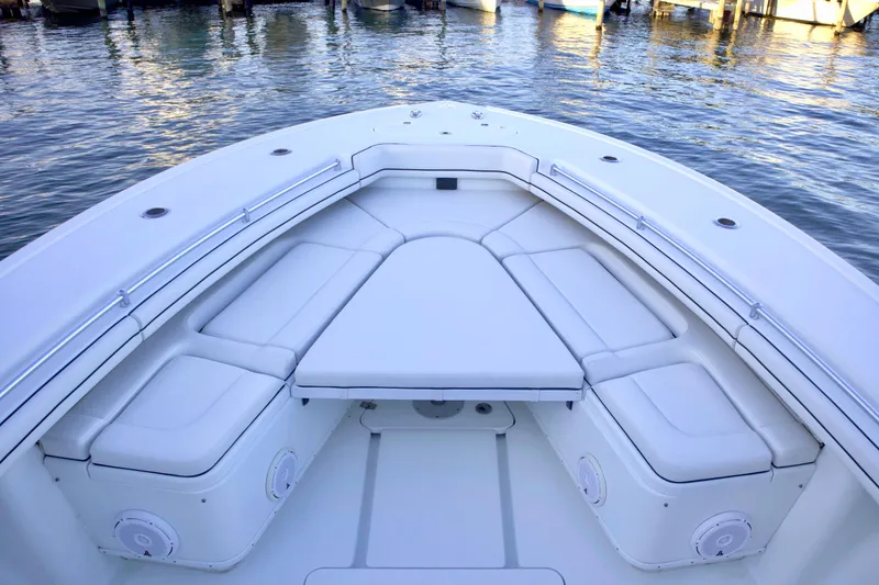 Slide: The Image of 2017 Yellowfin 39 Offshore boat interior with cushioned seating, docked on calm water. - 14