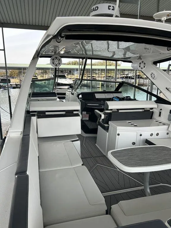 Slide: The Image of 2023 Monterey 378SS boat interior with modern seating and sleek design in a marina setting. - 42