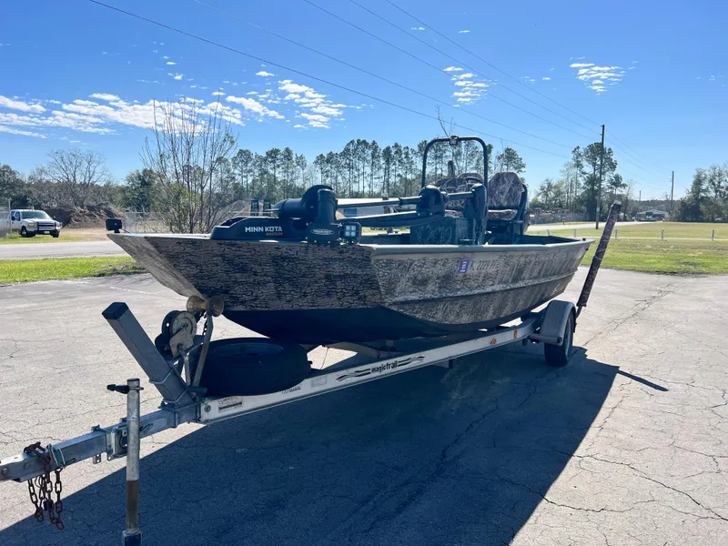 Slide: The Image of 2012 SeaArk 1872 boat on trailer, parked outdoors under clear blue sky. - 1